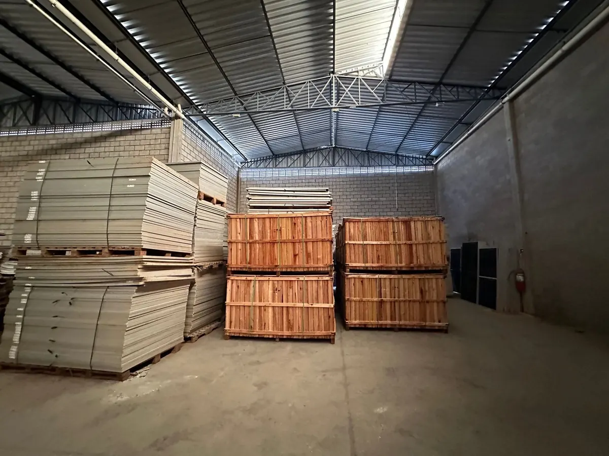Galpão com paletes altos de módulos fotovoltaicos empilhados à espera de reciclagem