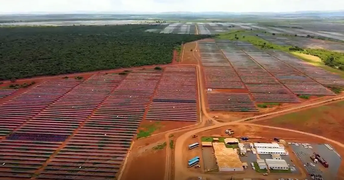 Vista aérea de uma usina solar com fileiras de módulos fotovoltaicos sobre terreno de solo vermelho